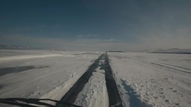 De auto rijdt met hoge snelheid op het transparante ijs van het Baikalmeer op een zonnige dag. Handheld pov shot van de camera — Stockvideo