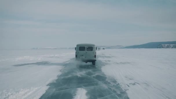 Baikal, obwód irkucki, Rosja - 18 marca 2021 r.: Widok przez szybę samochodu na przezroczysty lód jeziora Bajkał na drodze. Ręczne ujęcie z kamery w punkcie pov — Wideo stockowe