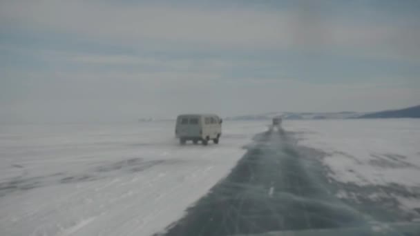 Вид через стекло автомобиля на прозрачный лед озера Байкал на дороге. Портативный фотоаппарат — стоковое видео