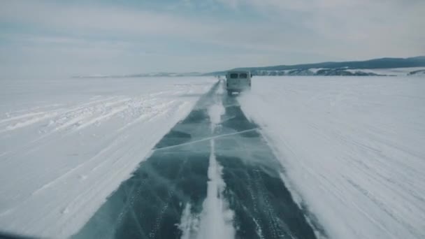 Widok konwoju minibusów UAZ podróżujących po przezroczystym lodzie jeziora Bajkał wzdłuż skalistego wybrzeża — Wideo stockowe