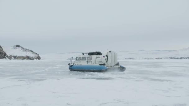 Baykal, Irkutsk Bölgesi, Rusya - 18 Mart 2021: Hovercraft Khivus insanları donmuş Baykal Gölü 'nden geçirdi ve büyük bir yelpazenin pervaneleriyle karları savurdu — Stok video