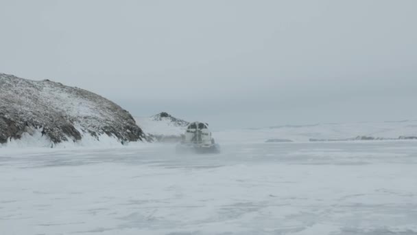冷凍湖バイカルの氷の上の観光客を島に運ぶ大きなファンを持つホバークラフトKhivus — ストック動画