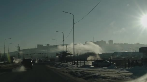 Buz gibi bir günde yarış pistinde yoğun trafik ve buhar bulutlarındaki tepedeki evlerin manzarası — Stok video