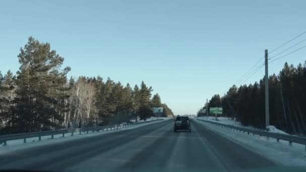 Regione di Irkutsk, Russia - 18 marzo 2021: Il movimento delle auto sulla strada principale circondato da una foresta fuori città e un panorama di un campo innevato — Video Stock