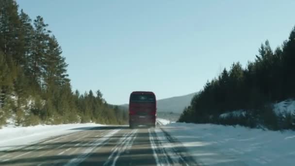 Baikal, regione di Irkutsk, Russia - 18 marzo 2021: Vista attraverso il parabrezza di un autobus rosso che guida avanti su una strada invernale. Colpo palmare punto di vista della fotocamera — Video Stock