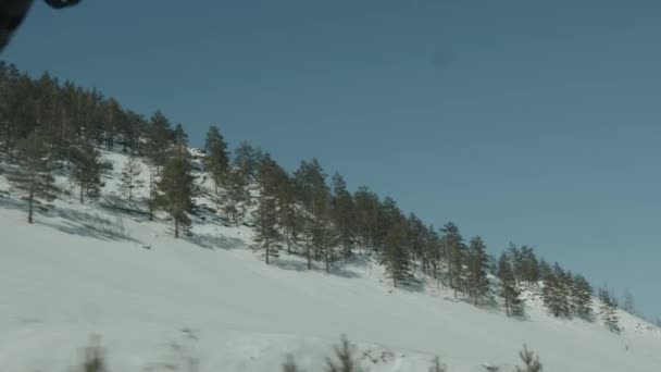 Vue à travers le pare-brise de la voiture jusqu'aux montagnes boisées enneigées. Vue pov portable de la caméra — Video