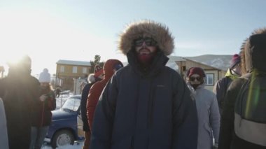 Irkutsk Bölgesi, Rusya - 18 Mart 2021: Kışlık ceketli ve güneş gözlüklü bir grup turist, dağlık bir bölgedeki bir otel kompleksinin karla kaplı bölgesinde duruyor