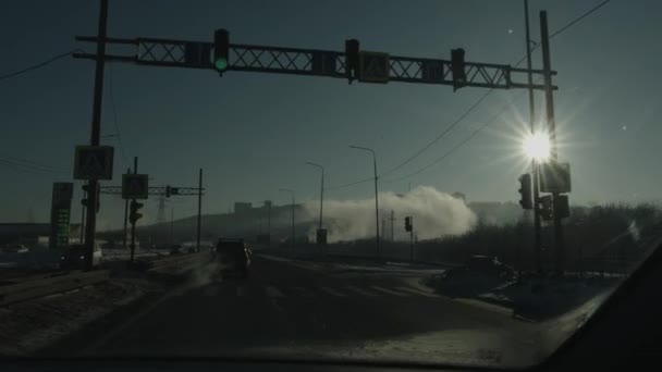 City view on hill in the clubs of steam in winter and the bright sun in the sky through the toned window of the car — Stock Video