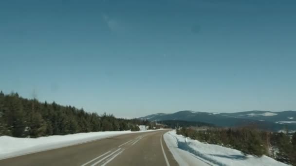 Vista attraverso il parabrezza di un'auto su un camion con tronchi sulla strada e un paesaggio invernale. Colpo palmare punto di vista della fotocamera — Video Stock