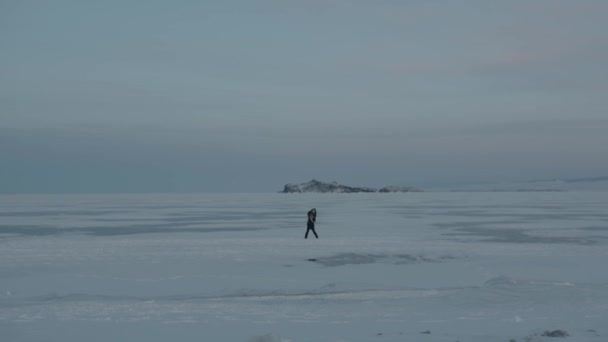Mladá dívka skáče a tančí na zasněženém ledu jezera Bajkal. Koncept štěstí a radosti — Stock video