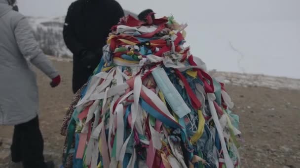 Una máscara médica entre las cintas de oración de colores en un pilar ritual budista durante la pandemia del coronavirus en Asia. Movimiento lento — Vídeo de stock