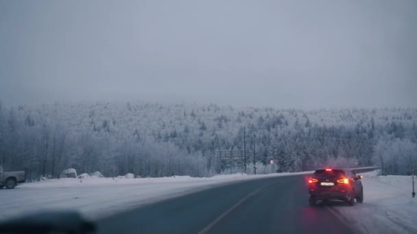Murmansk, Ρωσία - 10 Ιανουαρίου 2021: Θέα από το εσωτερικό του αυτοκινήτου σε ένα χιονισμένο δάσος κατά μήκος μιας προαστιακής εθνικής οδού. Έννοια χειμερινού ταξιδιού — Αρχείο Βίντεο