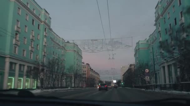 Murmansk, Rusia - 10 de enero de 2021: Tráfico ocupado y hermosas casas a lo largo de la carretera en la ciudad de invierno desde el interior del automóvil. pov de mano de la cámara — Vídeo de stock