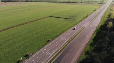 Bir yaz günü yeşil tarlalar ve ormanlar arasında otoyoldaki araba trafiğinin hava görüntüsü