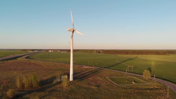 Minsk, Vitryssland - 20 maj 2021: Ovanifrån av en väderkvarn mot bakgrund av ett landsbygdslandskap och en bensinstation nära en vägkorsning — Stockvideo