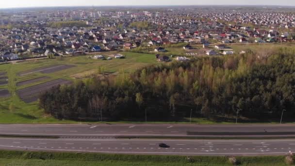 Letecký pohled na rušnou dálnici a okraj města se soukromými statky v letní den — Stock video