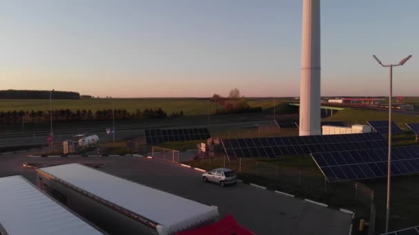 Drone shooting of solar panels near a truck parking and a gas station near a suburban highway — Stock Video