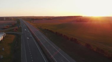 Yoğun bir banliyö otoyolu ve gün batımında yeşil tarlaları ve ormanı olan güzel kırsal manzarası.
