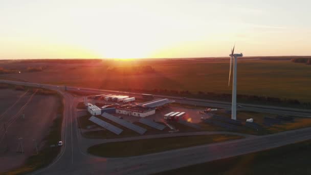 Minsk, Bělorusko - 20. května 2021: Letecký pohled na větrnou turbínu a solární panely u čerpací stanice na příměstské dálnici při západu slunce — Stock video