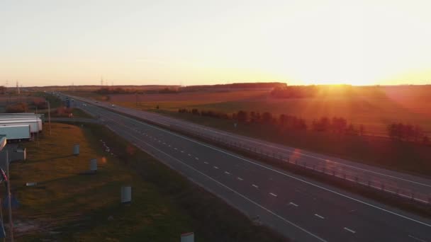 Mińsk, Białoruś - 20 maja 2021 r.: Widok z góry ruchliwej autostrady przy stacji benzynowej z przystankiem dla ciężarówek i liniami energetycznymi na horyzoncie o zachodzie słońca — Wideo stockowe