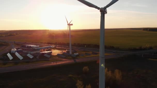 Minsk, Belarus - 20 mei 2021: Luchtfoto van draaiende bladen van een windmolen tegen de achtergrond van zonsondergang en benzinestation met zonnepanelen — Stockvideo