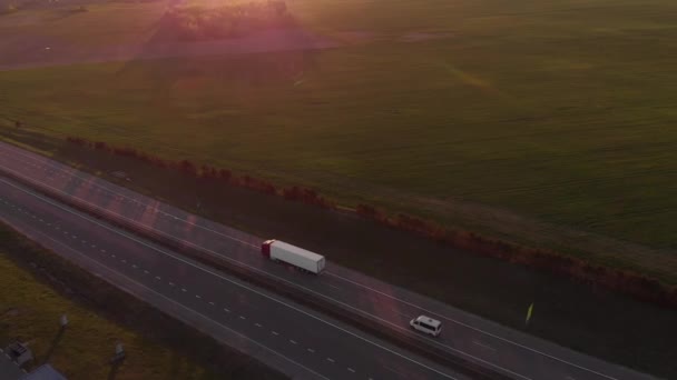 ベラルーシのミンスク-2021年5月20日：郊外の道路上の車の交通状況と日没時のガソリンスタンド近くの風車の刃の空中ビュー — ストック動画