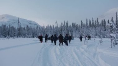 Murmansk, Rusya - 10 Ocak 2021: Erkekler ve kadınlar karlı bir yolda kış yürüyüşüne çıktılar ve doğaya hayran kaldılar. Yavaş çekim