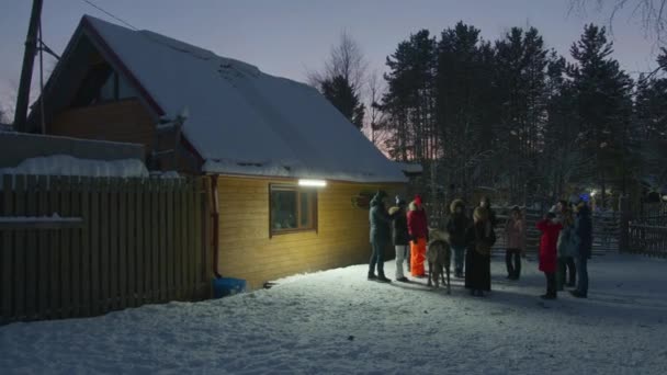 Murmansk, Russia - 10 gennaio 2021: un gruppo di turisti ispeziona e scatta fotografie con telefoni cellulari di renne durante un viaggio invernale la sera — Video Stock