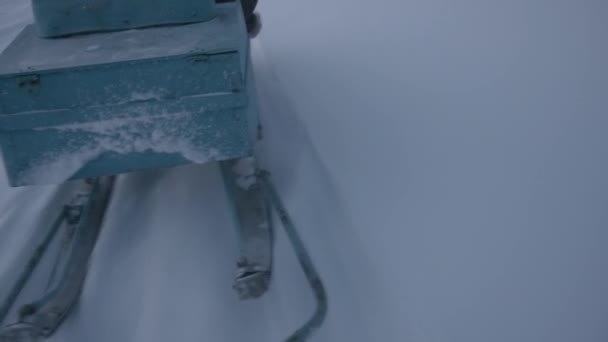 Uitzicht op een slee met ski 's bevestigd aan een sneeuwscooter tijdens het rijden op een besneeuwde weg — Stockvideo