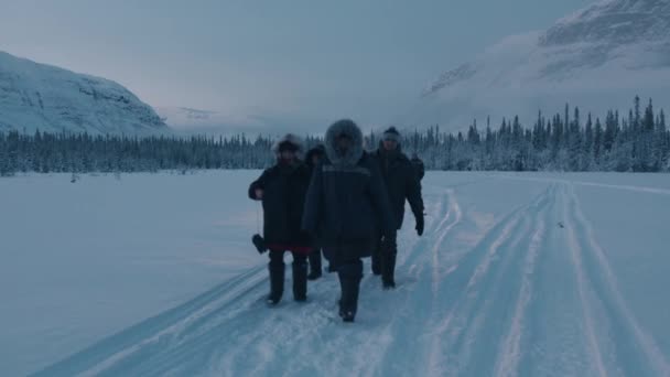 Murmansk, Ryssland - 10 januari 2021: En grupp turister vandrar längs ett snötäckt fält mot bakgrund av skogar och berg. Långsamma rörelser — Stockvideo