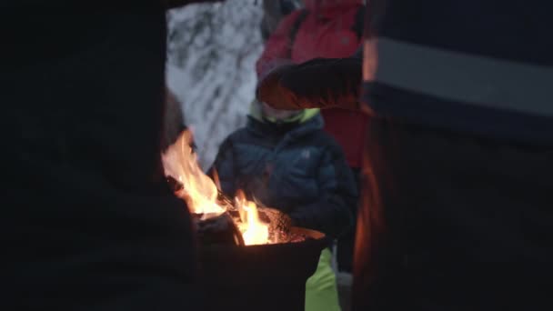 Een groep toeristen warmt zich op rond een kampvuur terwijl ze wandelen in het winterbos. Langzame beweging — Stockvideo
