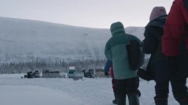 Murmansk, Rusya - 10 Ocak 2021: Kış yürüyüşü sırasında bir grup turist ormanlara ve dağlara giden karlı bir yoldan geçiyor. Arka plan