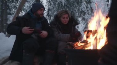 Murmansk bölgesi, Rusya - 10 Ocak 2021: Bir grup turist ateşin yanındaki bir kış ormanında oturup konuşuyorlar