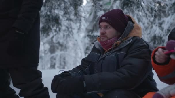 Murmansk, Rusland - 10 januari 2021: Een man zit tussen vrienden in een winterbos te praten en te glimlachen — Stockvideo