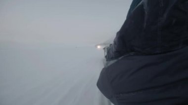 Kutup gecesinde karlı bir yolda turistlerle kızaklı kar arabalarından gelen tren.