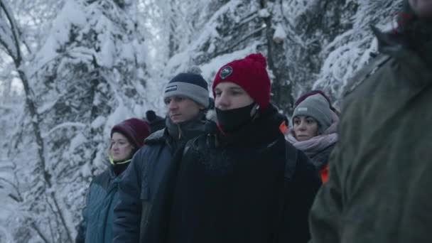 Regio Moermansk, Rusland - 10 januari 2021: Een groep toeristen staat tegen de achtergrond van een besneeuwd bos tijdens een winterwandeling — Stockvideo