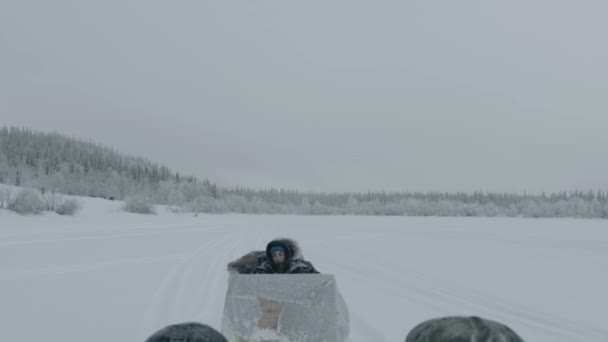 Murmansk region, Russia - January 10, 2021: Snowmobiles carry sledges with tourists across a snow field. Handheld pov shot of camera — стоковое видео