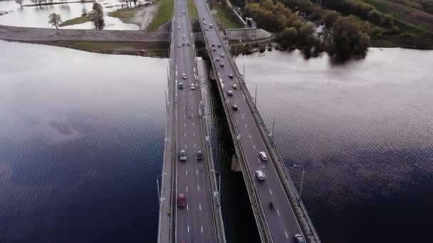 Вид з повітря на зайнятий рух по подвійному мосту над річкою і дерева затоплені під час повені на березі — стокове відео