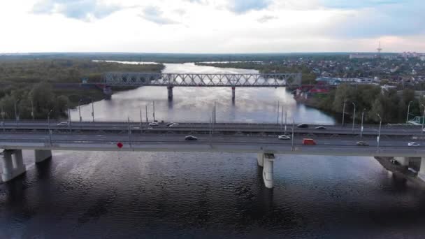 Drone shooting of a panorama of a part of the city and view of double road and railway bridges across the river — стоковое видео