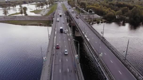 Вид с воздуха на оживленное движение по двойному мосту через широкую реку и вид на затопленные деревья на берегу — стоковое видео