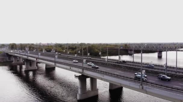 Безпілотне відео легкових автомобілів на подвійному дорожньому мосту та залізничному мосту на околиці міста — стокове відео