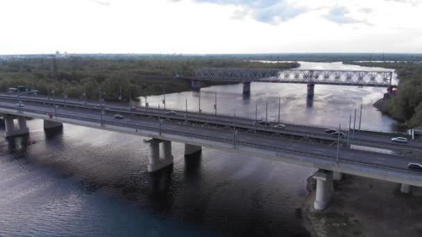 Flygfoto över livlig trafik på den dubbla vägbron över floden och järnvägsbron i utkanten av staden — Stockvideo