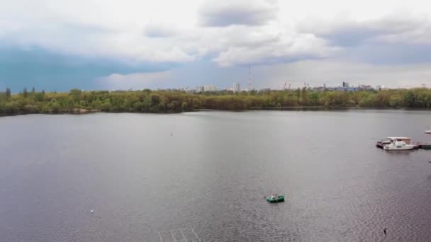 Vista aérea de una pareja en un barco sobre el río en las literas con yates y un panorama de la ciudad en la distancia — Vídeos de Stock