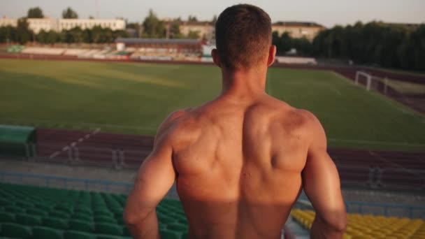一个赤身裸体的年轻人站在体育场里，仰面反射肌肉。慢动作 — 图库视频影像