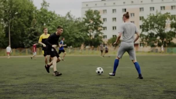 Игроки футбольной команды тренируются на футбольном поле в жилом районе города и практикуются в игровых моментах. Медленное движение — стоковое видео