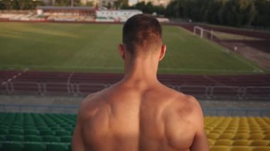 Genç kaslı bir adam stadyumda antrenman yapıyor ve tribünün merdivenlerinden aşağı koşuyor. Ağır çekim. Sonraki çekim