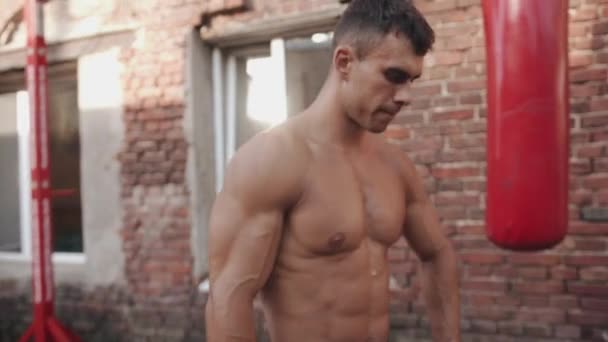 Muskelprotz mit nacktem Oberkörper trainiert auf dem Sportplatz und atmet in der Pause zwischen den Übungen wieder auf — Stockvideo