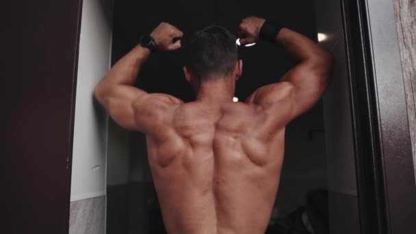 De bodybuilder toont het resultaat van zijn training en toont een pose voor de breedste spieren van de rug — Stockvideo
