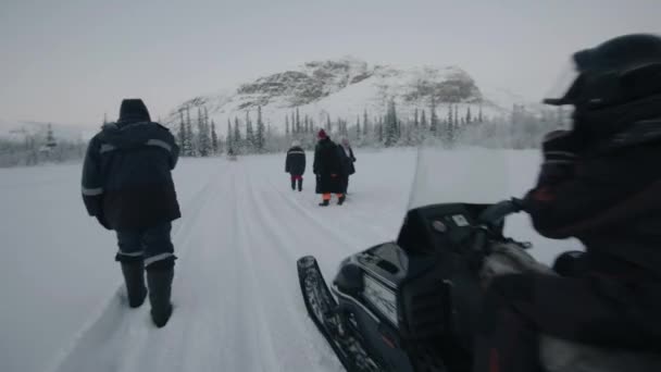 2021年1月10日，俄罗斯摩尔曼斯克地区：一名男子驾驶雪地摩托与木制雪橇经过一群游客。慢动作 — 图库视频影像