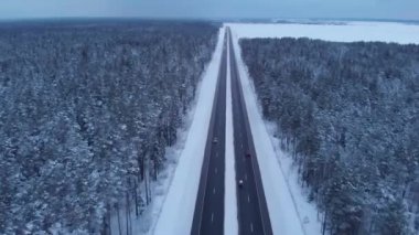Kentin dışındaki otoyolda kar tarlaları ve ormanların arasında yoğun trafiğin havadan görüntüsü